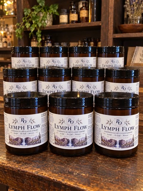 Jars of Lymph Flow lymphatic body balm stacked on a wooden counter