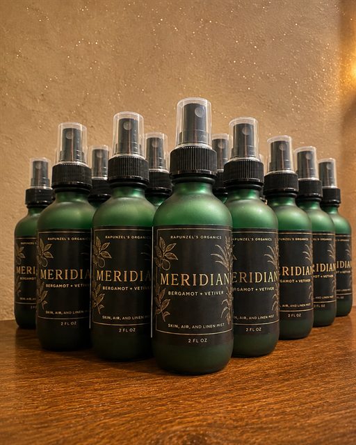 Green glass bottles of Meridian bergamot and vetiver mist
